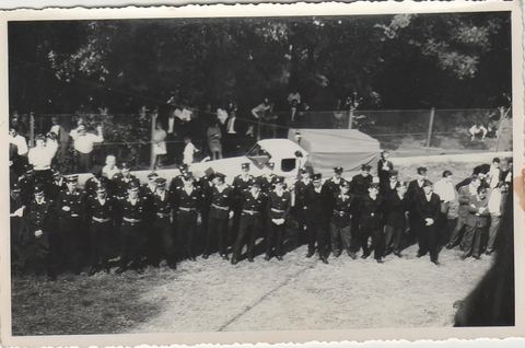Archiwalne czarno-białe zdjęcie z obchodów 60-lecia: druhowie ustawieni w szeregu na placu przed jednostką, w tle widzowie
