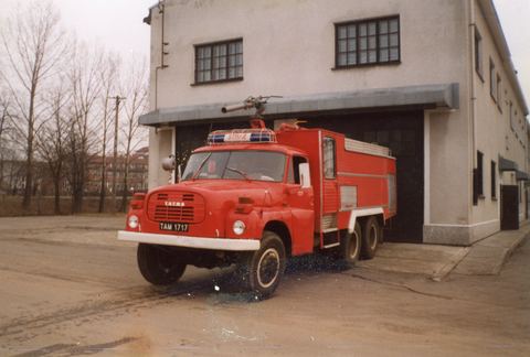 Czerwony samochód pożarniczy Tatra 148 stojący przed budynkiem remizy